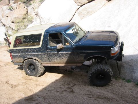 1994 Ford Bronco - Mud-splattered 1994 Ford Bronco on a rocky trail.