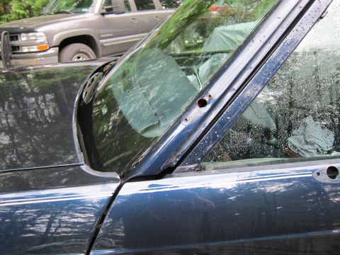 1991 Ford LTD Crown Victoria - Close-up of a dark blue sedan's side, showing the door and window frame, with a gray SUV in the background.