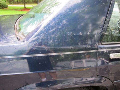 1991 Ford LTD Crown Victoria - Rear quarter panel of a dark blue 1991 Ford Crown Victoria LTD, showing bullet holes and chrome trim.
