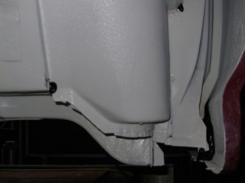 White painted undercarriage sheet metal with maroon paint strip at right edge
