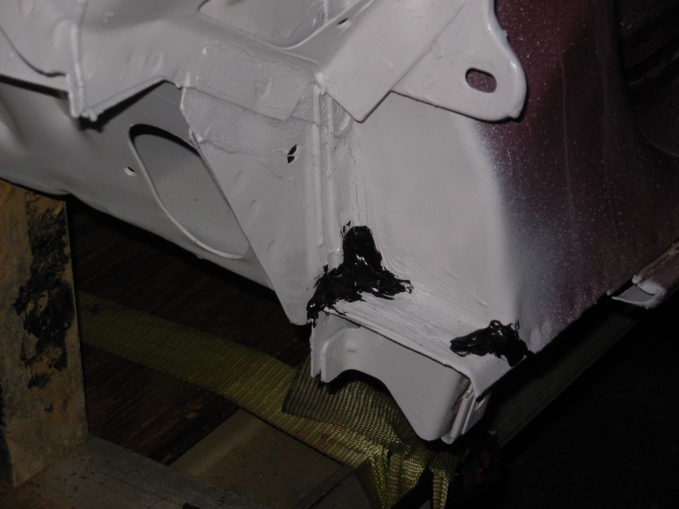 White-painted body panel with black seam sealer, maroon edge, on wood and yellow strap