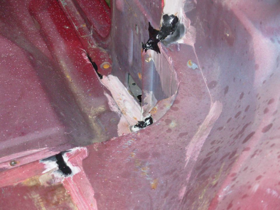 There were several leaks at the bottom of the passenger B-pillar that I've filled, and some that I created.  Inside the pillar (center of the photo), I removed 2 pushpins, a filler plate, and a layer of foam that covered a drain hole.  I'll patch the smaller holes & install the earlier rubber drain plug.  I may also fill the valley between the floor & the pillar's base (the white area).