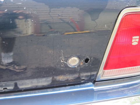1991 Ford LTD Crown Victoria - The rear of a blue sedan shows a missing fuel door and some rust around the opening.