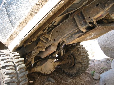 1994 Ford Bronco - The underside of a heavily soiled off-road vehicle is visible, showing its suspension and large tires.