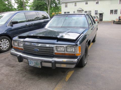 1991 Ford LTD Crown Victoria - Dark blue sedan parked next to a minivan, with its hood open. The license plate is visible.