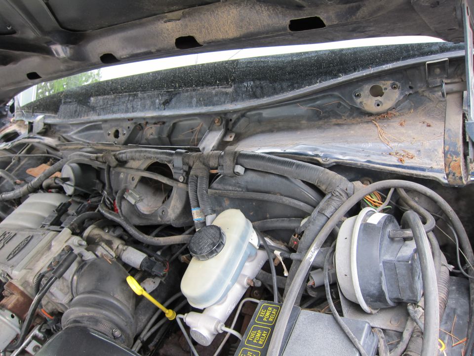 Engine bay with brake fluid reservoir and wiring harnesses