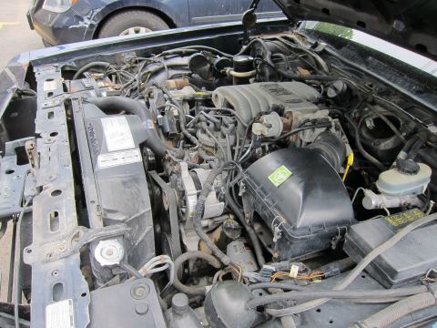 1991 Ford LTD Crown Victoria - Engine bay details of a Ford vehicle, with another car visible in the background.