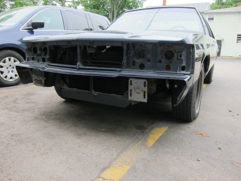 1991 Ford LTD Crown Victoria - A dark sedan's front end is disassembled, parked next to a blue minivan.