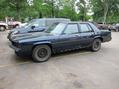 1991 Ford LTD Crown Victoria - Side view of a dark blue 1991 Ford Crown Victoria LTD, showing its distinctive body style and missing front grille.