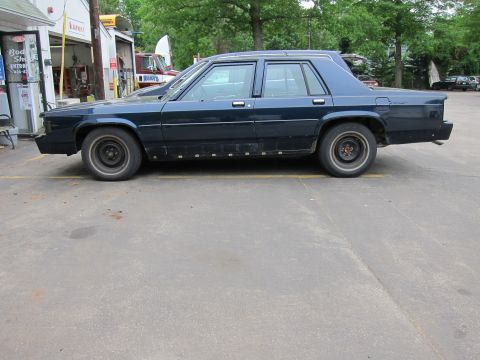 1991 Ford LTD Crown Victoria - Side profile of a 1991 Ford Crown Victoria LTD sedan parked in front of a garage.