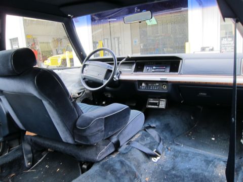 1991 Ford LTD Crown Victoria - The interior of a car shows worn blue velour seats and a dashboard with an aftermarket radio and control panel.