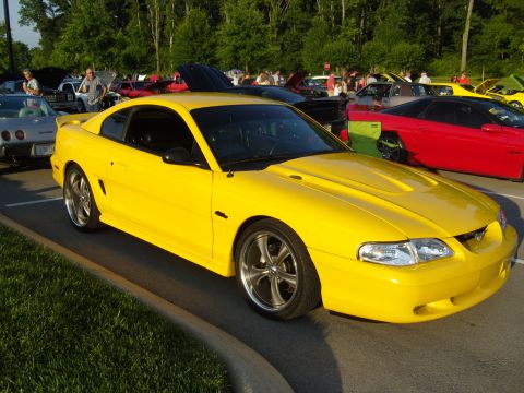 2007 Ford Mustang - Yellow Ford Mustang coupe with aftermarket wheels at a car meet.