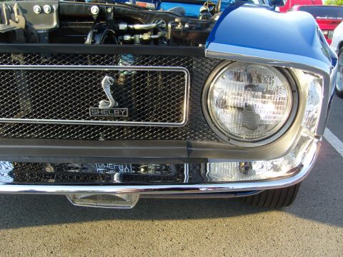 2007 Ford Mustang - Front view of a blue Shelby Mustang, its iconic cobra emblem on the grille and chrome accents.