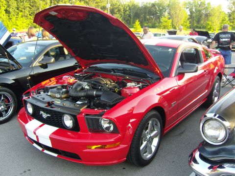 2007 Ford Mustang - Red 2007 Ford Mustang with hood open at a car show, white racing stripes.