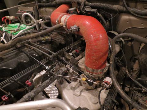 2005 Jeep Wrangler - Close-up view of an engine bay, focusing on a red intake hose and various engine components.