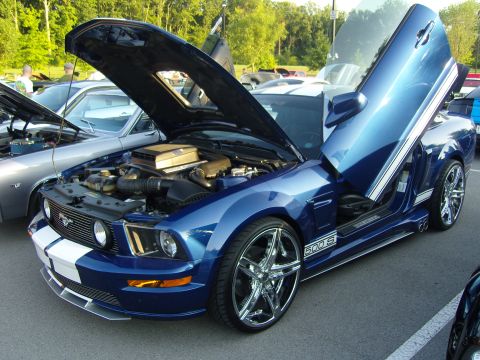 2007 Ford Mustang - Custom 2007 Ford Mustang GT500 with lambo doors and hood open at a car show.