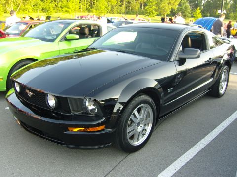 2007 Ford Mustang - Black 2007 Ford Mustang GT parked at a car show with other vehicles visible.