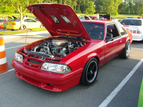 2007 Ford Mustang - A red coupe with its hood open is parked at an outdoor event, with other vehicles visible in the background.