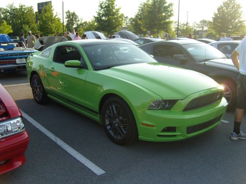 2007 Ford Mustang - A bright green Ford Mustang is parked in a lot with other vehicles.