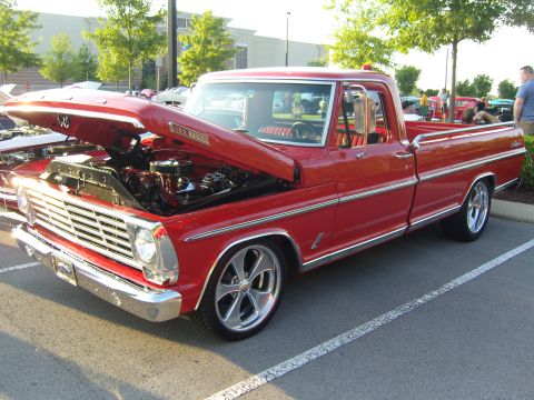 2007 Ford Mustang - A red 1967 Ford F-100 pickup truck is parked with its hood open, revealing the engine.