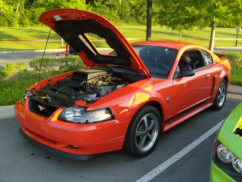 2007 Ford Mustang - This orange 2007 Ford Mustang coupe is shown with its hood open, revealing the engine bay.
