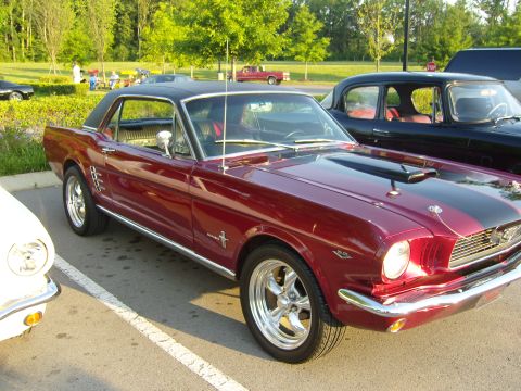 2007 Ford Mustang - A classic red 1965 Ford Mustang coupe is parked next to other vehicles.