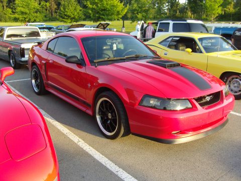 2007 Ford Mustang - A red 2007 Ford Mustang is parked at an outdoor car meet with other vehicles visible.