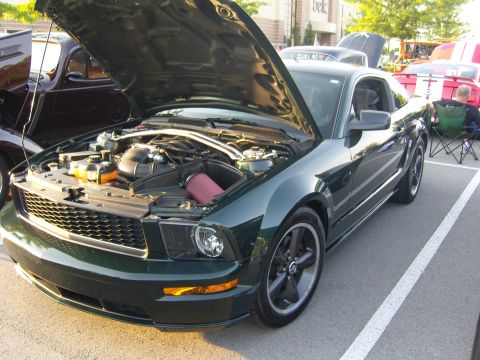2007 Ford Mustang - A dark green 2007 Ford Mustang is parked with its hood up, revealing the engine bay.