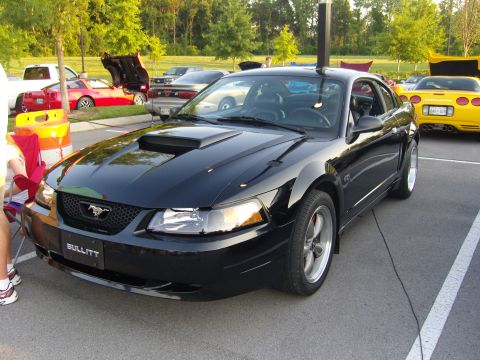 2007 Ford Mustang - A black Ford Mustang with a hood scoop and 'Bullitt' badging is parked in a lot with other vehicles.