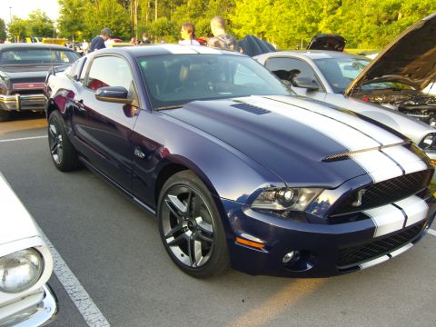 2007 Ford Mustang - A dark blue 2010 Ford Mustang GT500 with white racing stripes is parked at an outdoor event.
