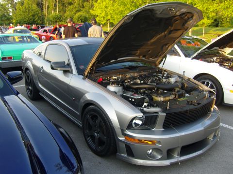 2007 Ford Mustang - A silver 2007 Ford Mustang coupe is parked with its hood open, revealing the engine bay.