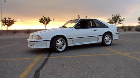 1989 Ford Mustang - White 1989 Ford Mustang GT parked in a lot during sunset.