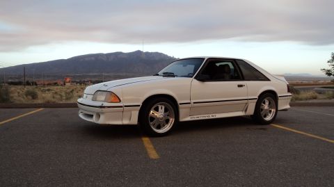 1989 Ford Mustang - A white 1987 Ford Mustang GT is parked in a lot with a mountain range visible in the distance.