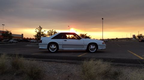 1989 Ford Mustang - Side view of a white 1989 Ford Mustang GT parked in a lot during sunset.
