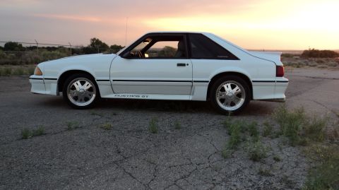 1989 Ford Mustang - Side view of a white 1989 Ford Mustang GT with a spoiler and GT badging.