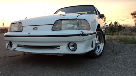 1989 Ford Mustang - Front view of a white 1989 Ford Mustang with chrome wheels parked outdoors.