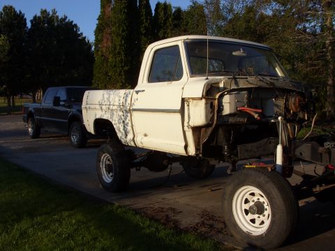 1967 Ford F-250 - A white 1973 Ford F-Series pickup truck is missing its front end, parked beside a dark pickup truck.