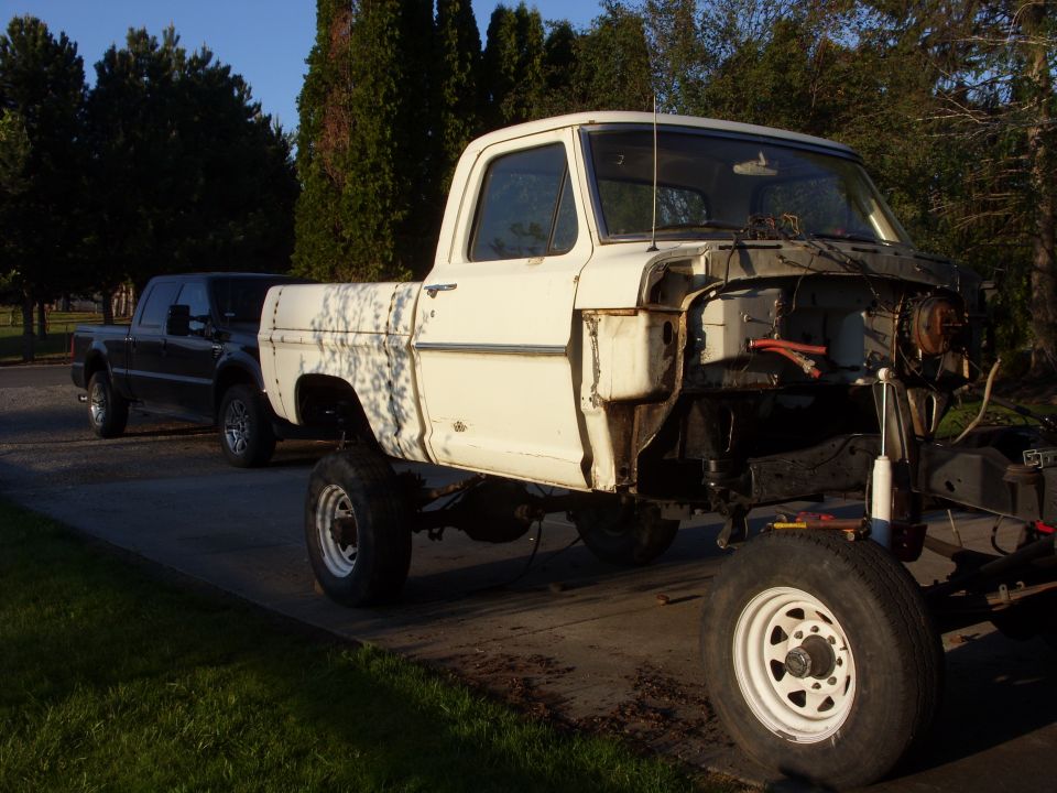 White 1973 Ford F-Series pickup truck, front end removed, parked next to a dark pickup