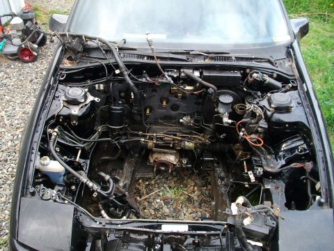 1989 Ford Probe - The engine bay of a 1989 Ford Probe is shown with the engine removed, revealing its internal components and wiring.