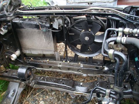 1989 Ford Probe - The front end of a car is disassembled, revealing the radiator and cooling fan assembly.