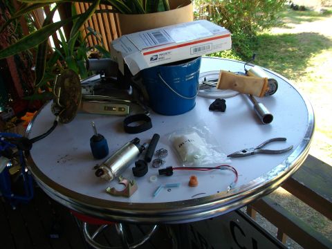 1989 Ford Probe - Various fuel pump components, including a new pump and filter, are spread across a table, suggesting a repair or replacement project.