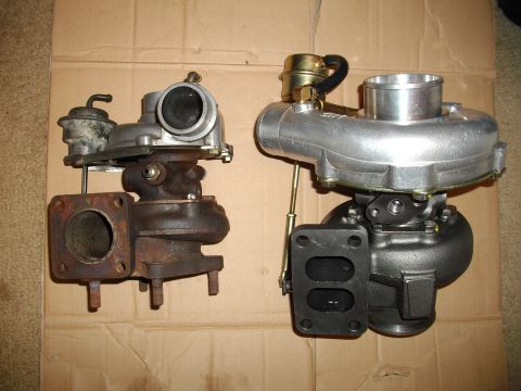 1989 Ford Probe - Comparison of a used turbocharger next to a new one, both resting on a cardboard background.