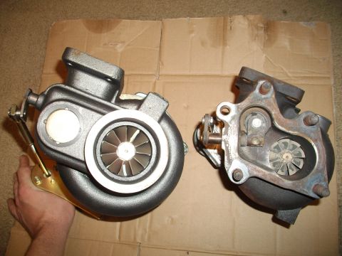 1989 Ford Probe - Two turbochargers are displayed on a cardboard surface, with one being held by a person's hand.