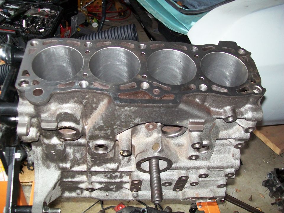 Engine block with four cylinders visible, on a stand