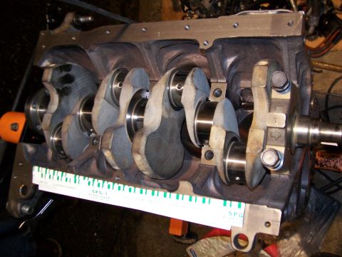 1989 Ford Probe - Engine crankshaft assembly with a feeler gauge for measurement. No year is discernible.