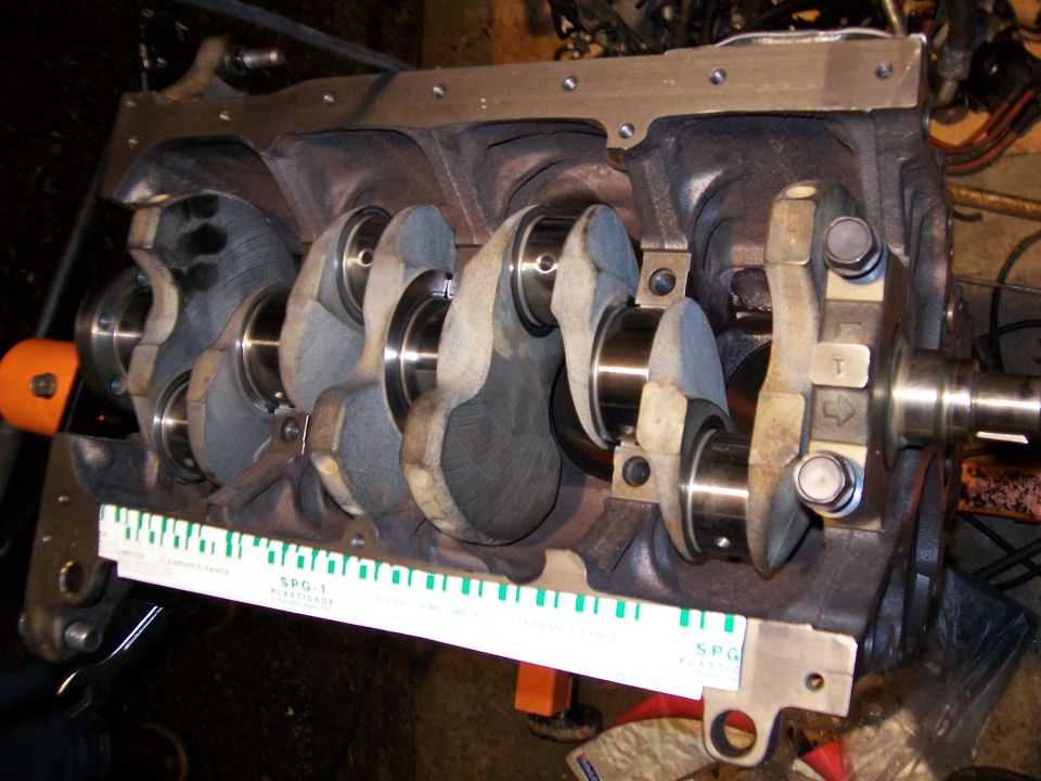 Engine crankshaft with a feeler gauge laid across it. "SPG-1" is visible on the gauge