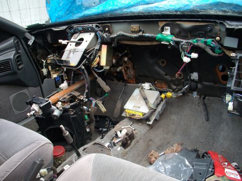 1989 Ford Probe - The interior of a car has been stripped down, revealing complex wiring and electronic components beneath the dashboard.