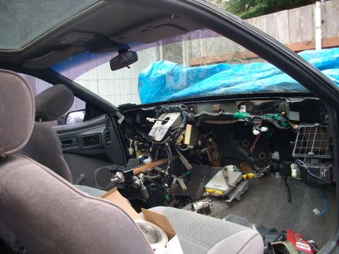 1989 Ford Probe - The dashboard of a car is disassembled, revealing a complex network of wires and electronic components.