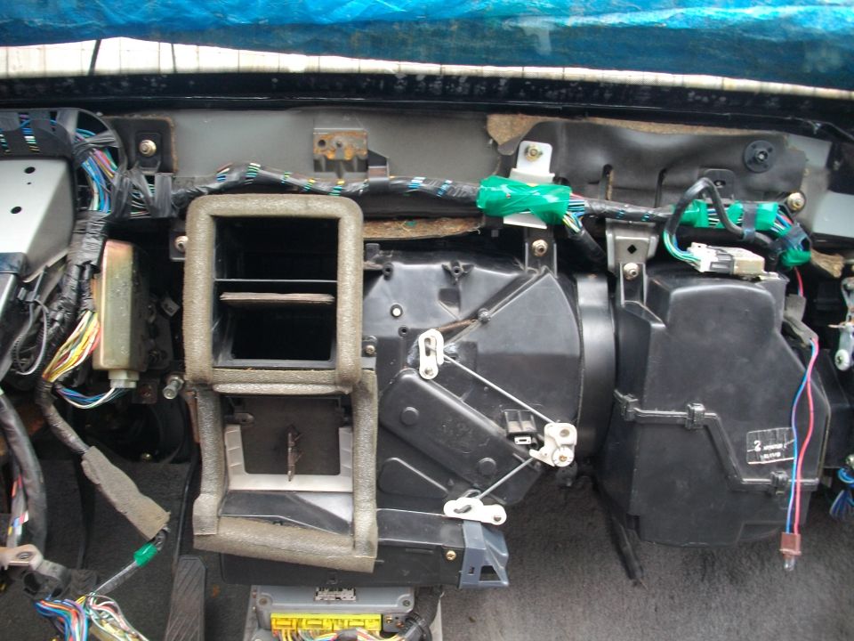 Disassembled car dashboard showing HVAC unit, vents, and wiring harness