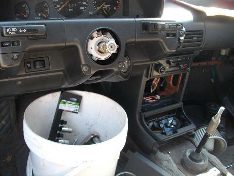 1989 Ford Probe - Dashboard interior with steering column removed and tools in a bucket, suggesting repair work.